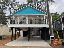 Charming elevated beach home with a blue accent roof, covered parking, and a spacious balcony at 6001 S Kings Hwy., Myrtle Beach, SC 29575