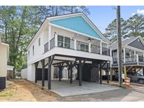 Charming raised beach house with blue accents and a spacious covered parking area at 6001 S Kings Hwy., Myrtle Beach, SC 29575