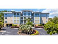 Beautiful condo complex exterior with lush landscaping and a circular driveway with palm trees at 1352 Villa Marbella Ct. # 1-204, Myrtle Beach, SC 29572