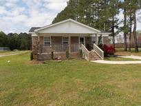 Charming brick home with a covered porch and well-manicured lawn featuring vibrant red flowers at 1465 Dirty Branch Rd., Conway, SC 29527