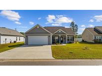 Charming single-story home featuring a well-manicured lawn, gray siding, and a two-car attached garage at 237 Copperwood Loop, Conway, SC 29526