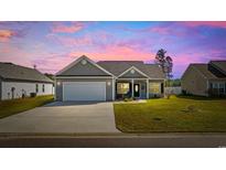 Charming single-story home with a well-manicured lawn and inviting curb appeal at dusk at 237 Copperwood Loop, Conway, SC 29526