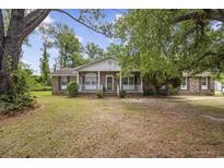 Charming brick home with a covered front porch and mature trees in a serene, wooded setting at 2560 Wise Rd., Conway, SC 29526