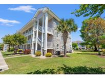 Beautiful exterior of a building with stone accents, private balconies, and lush landscaping at 4683 Wild Iris Dr. # 204, Myrtle Beach, SC 29577