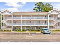 Three-story condo building featuring white trim, multiple balconies, parking, and a well-maintained landscape at 4787 Wild Iris Dr. # 101, Myrtle Beach, SC 29577