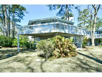 Charming elevated home with a spacious wraparound deck, surrounded by lush landscaping and mature trees at 742 Tall Oaks Ct., Myrtle Beach, SC 29588