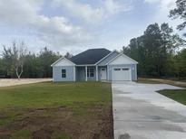 Charming single-story home featuring blue siding, white trim, attached garage and a neatly landscaped front yard at 10522 W Highway 19, Loris, SC 29569