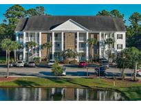 Charming condo building with brick accents, white columns, and lush landscaping overlooking a serene pond at 106 Birch N Coppice Dr. # 2, Surfside Beach, SC 29575