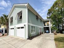 Inviting home showcasing a spacious two-car garage, serene pastel siding and a lush landscape at 1131 Camellia Dr., Surfside Beach, SC 29575