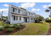 A two-story townhome with a well-maintained lawn and landscaping and neutral exterior paint and black shutters at 1890 Colony Dr. # 17S, Myrtle Beach, SC 29575