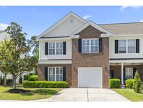 Charming brick and vinyl-sided townhome with well-maintained landscaping, black shutters and attached garage at 220 Connemara Dr. # A, Myrtle Beach, SC 29579