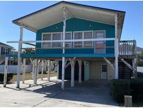 Elevated teal house featuring a pink door and under house parking at 317 29Th Ave. N, North Myrtle Beach, SC 29582