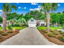Charming one-story home with an attached garage, tidy landscaping, and long driveway lined with palm trees at 4482 Fringetree Dr., Murrells Inlet, SC 29576