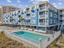 Stunning exterior of a blue condo building featuring a pool with ample seating and lush greenery at 5600 Ocean Blvd. N # A11, North Myrtle Beach, SC 29582