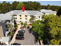 Exterior view of a condominium complex with tan siding and a gray roof plus parking at 70 Mingo Dr. # 3-E, Pawleys Island, SC 29585