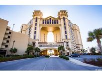 Grand building exterior featuring a distinctive archway, palm trees, and manicured landscaping at 100 North Beach Blvd. # 313, North Myrtle Beach, SC 29582