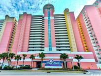 A large condo building with colorful exterior near a green landscape and clear skies at 2701 S Ocean Blvd. # 1507, North Myrtle Beach, SC 29582