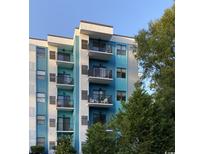 Exterior shot of condo building with private balconies, blue and white accents and mature trees at 5001 Little River Rd. # E-410, Myrtle Beach, SC 29577