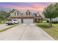 Charming home boasts a brick facade, two-car garage, and well-manicured lawn at 524 Cottage Oaks Circle, Myrtle Beach, SC 29579
