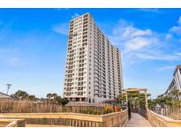 Condo exterior with a bright white facade, blue sky, and boardwalk access in a prime beachside location at 5905 S Kings Hwy. # 805, Myrtle Beach, SC 29575