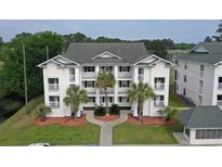 Low aerial of condominiums with tropical landscaping, balconies, and partial lake view at 649 Tupelo Ln. # 13A, Longs, SC 29568