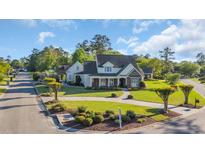 Stunning home with manicured landscaping, circular driveway and a mix of stone and neutral colored siding at 107 Long Bay Golf Pl., Longs, SC 29568