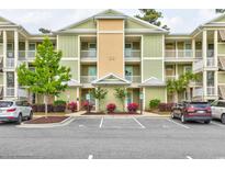Inviting condo exterior with manicured landscaping, building number, and convenient parking at 128 Puffin Dr. # 1E, Pawleys Island, SC 29585