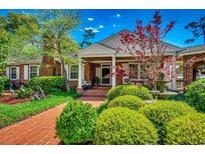 Charming brick home with a lush landscaped yard, brick walkway, front porch, and water fountain at 141 N Gate Rd., Myrtle Beach, SC 29572