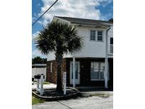 Two story beach condo with brick foundation and a lush palm tree at 1502 Yaupon Dr. # A-1, Myrtle Beach, SC 29577