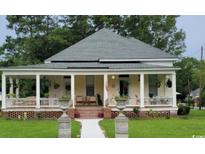 Charming yellow house featuring a welcoming front porch and manicured lawn at 402 Gibson St., Marion, SC 29571