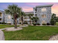 Beautiful condo exterior with stone accents, palm trees and well-manicured lawn at 4709 Wild Iris Dr. # 101, Myrtle Beach, SC 29577