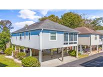 Coastal home featuring a stilt foundation, screened porch, and manicured landscaping at 820 9Th Ave. S, North Myrtle Beach, SC 29582