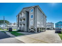 Three-story condo building on stilts with a large concrete parking pad and private balconies at 1208 S Ocean Blvd. # H, North Myrtle Beach, SC 29582