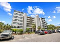 Low-angle view of a multistory condo building with ample parking, landscaping, and beautiful blue sky at 311 71St Ave. N # 3-D, Myrtle Beach, SC 29572