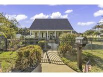 Charming home featuring a well-kept lawn, black fence, and inviting front porch, offering curb appeal at 407 15Th Ave. S, North Myrtle Beach, SC 29582