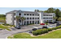 Attractive condo building with neat landscaping, ample parking, and a view of the lake from the parking lot at 4503 W Harbour Ct. # S9, Little River, SC 29566