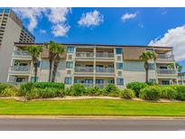 Beach condo exterior showcasing multiple floors with balconies, lush landscaping, and palm trees at 5601 N Ocean Blvd. # A-206, Myrtle Beach, SC 29577