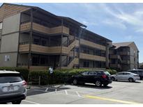 A view of the condo building's exterior with a parking lot and neatly trimmed hedges at 9501 Shore Dr. # D-237, Myrtle Beach, SC 29572