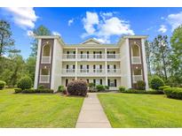 Building 21 boasts an attractive facade, multiple balconies, and is framed by a lush green lawn and bright blue skies at 1204 River Oak Dr. # 25-A, Myrtle Beach, SC 29579