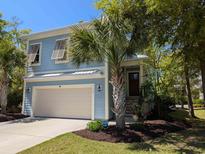 Charming two-story home with a well-maintained yard and palm trees, showcasing its inviting curb appeal at 18 Trigger Fish Ln., Murrells Inlet, SC 29576