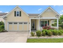 Charming home with a two-car garage, yellow siding, a porch and a beautifully landscaped front yard at 1881 Willowcress Ln., Myrtle Beach, SC 29577