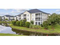 Beautiful exterior view of a condo building with pond, landscaping and screened-in porches at 2090 Cross Gate Blvd. # 202, Surfside Beach, SC 29575