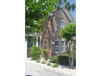 Charming brick home featuring a manicured front yard with lush landscaping and a mature palm tree at 22 Woodhaven Dr. # C, Murrells Inlet, SC 29576