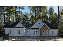 Charming new construction home with a covered front porch and a modern farmhouse design nestled amongst mature trees at 25 Pinewood Dr., Carolina Shores, SC 28467