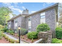 Brick condo building with manicured landscaping, sidewalk, and decorative street lighting on a sunny day at 404 75Th Ave N # G, Myrtle Beach, SC 29572