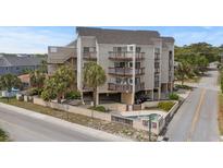 Three-story condo building with multiple balconies and covered parking, surrounded by lush landscaping and street access at 4500 S Ocean Blvd. # 4, North Myrtle Beach, SC 29582