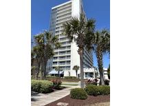 Beautiful exterior view of condo building and lush landscaping with palm trees on a sunny day at 5511 North Ocean Blvd. # 105, Myrtle Beach, SC 29577