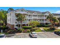 Three-story condo building with white siding, balconies, and palm trees in a well-maintained complex at 5751 Oyster Catcher Dr. # 431, North Myrtle Beach, SC 29582