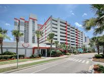 View of a condominium building with a connected parking garage and beautiful tropical landscaping at 7200 Ocean Blvd. N # 664, Myrtle Beach, SC 29572