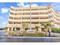 View of the condo's exterior with multiple floors, parking garage, and signage at 1581 S Waccamaw Dr. # 302, Garden City Beach, SC 29576